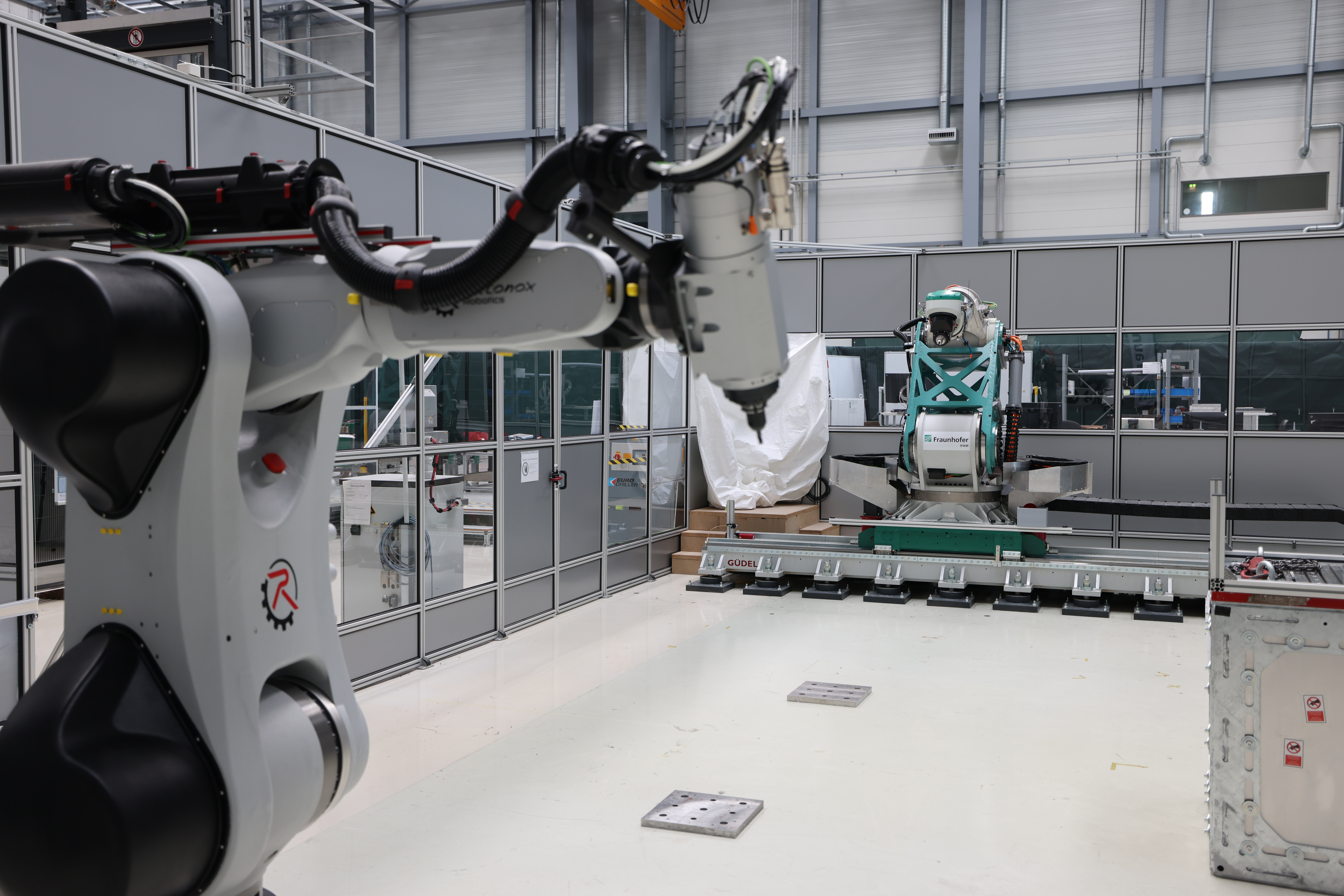Technology transfer to industrial applications: In the background the flexible milling kinematics developed at Fraunhofer IFAM, in the foreground the jointly developed product solution from autonox Robotics. Technologietransfer für die industrielle Anwendung: Im Hintergrund die am Fraunhofer IFAM entwickelte flexible Fräskinematik, im Vordergrund die gemeinsam entwickelte Produktlösung von autonox Robotics.